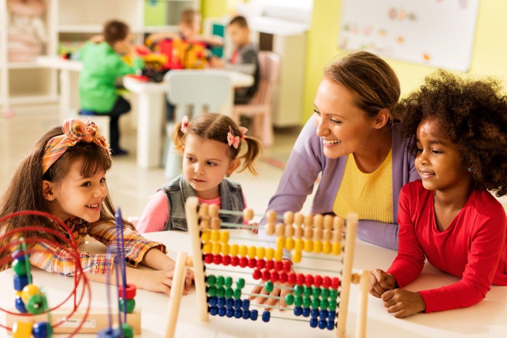 Little girls and teacher learning at preschool.